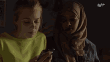 two women are standing next to each other and the bottom right corner of the screen says m +