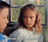 a boy and a girl are sitting on a bus and the girl is asking the boy are you stupid or something .