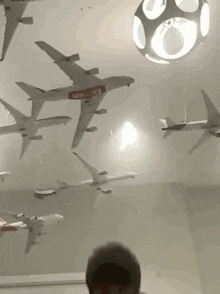 a man is standing in front of a wall with a lot of airplanes on it .