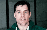 a man in a green hoodie is making a funny face .