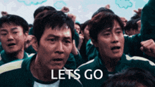 a group of men are standing in a crowd and the word lets go is on the screen
