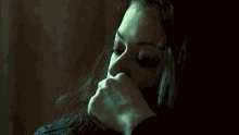 a woman is covering her mouth with her hand and looking at the camera .