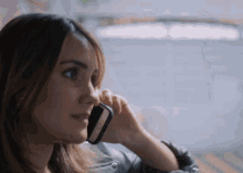 a woman is talking on a cell phone while looking out the window