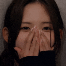 a close up of a woman covering her face with her hand