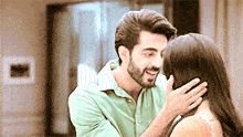 a man and a woman are standing next to each other and the man is touching the woman 's face .