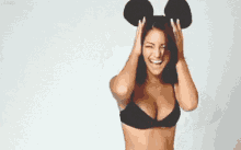 a woman in a black bra is wearing a pair of mickey mouse ears on her head