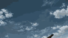 a close up of a person 's leg against a blue sky with clouds