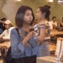 two women are standing next to each other in a restaurant .