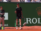 a man holding a tennis racquet in front of a sign that says roi
