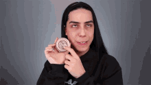 a woman with long black hair is holding a powder in her hand .