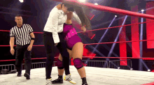 two women are wrestling in a ring with a referee