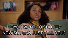 a woman is sitting on a couch and says do you want to shut up now so i can just tell you