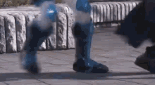 a person wearing a blue superhero costume is walking on the sidewalk .