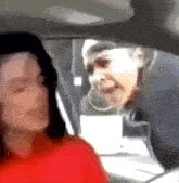 a woman in a red shirt is sitting in a car with another woman behind her