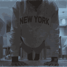 a man is doing push ups wearing a new york sweatshirt