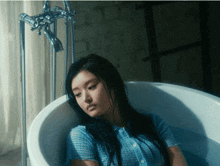 a woman sits in a bathtub with her head on the edge
