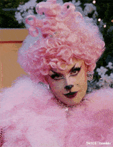 a drag queen wearing a pink wig and a pink feathered coat