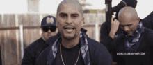 a man with a bandana around his neck is standing in front of a worldstarhiphop.com banner