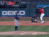 a baseball game is being played in front of a geico banner