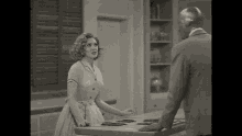 a man and a woman are standing in a kitchen .