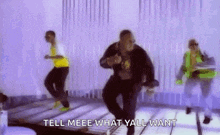 a group of people are dancing on a stage with the words `` tell meee what yall want '' .