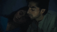 a man and a woman are laying on a bed in the dark .