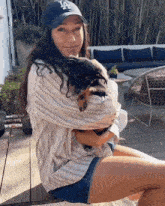 a woman wearing a la hat holds a puppy in her arms