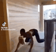 a man is crawling on the floor in a hallway with a dog .