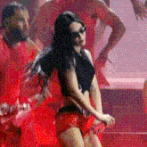 a woman in a black top and red shorts is dancing