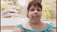 a woman is wearing a blue shirt and a white bra and is making a funny face .