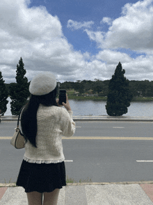 a woman is taking a picture of a lake with her cell phone