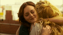 a woman hugging another woman with her eyes closed