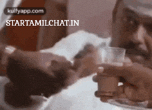a man is drinking from a glass with the website starttamilchat.in written on the bottom