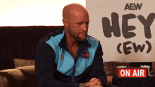 a man is sitting in front of a sign that says hey ( ew )