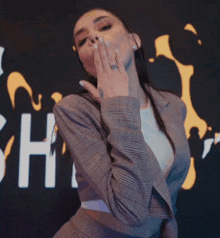 a woman blowing a kiss in front of a sign that says " sh "