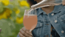 a woman is pouring a pink drink into a glass .