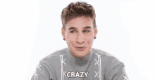 a young man wearing a gray sweater is smiling and making a funny face .