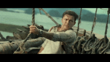 a man is holding onto a rope on a boat in the water