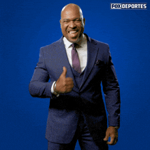 a man in a suit giving a thumbs up in front of a fox deportes sign