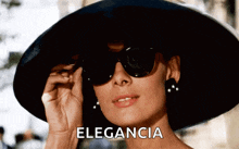 a woman wearing a hat and sunglasses has the word elegancia written on the bottom