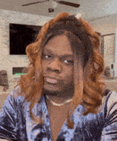 a man is wearing a wig and a headband and making a funny face .
