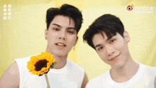 two men standing next to each other with one holding a sunflower and the other a weibo logo