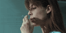 a woman smoking a cigarette with a blue background