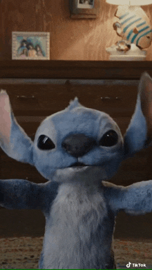 a stuffed animal that looks like stitch is standing in front of a dresser .
