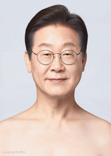 a man without a shirt is wearing glasses and smiling for the camera
