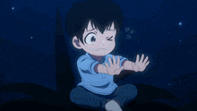a little boy is sitting in a dark room with his hands up