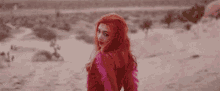 a woman with long red hair is standing in the desert .
