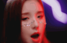 a close up of a woman 's face with red and purple lights behind her