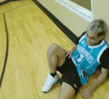 a man wearing a jersey that says ' angels ' on it is sitting on the floor
