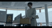 a woman stands in front of a podium with a sign that says wc on it